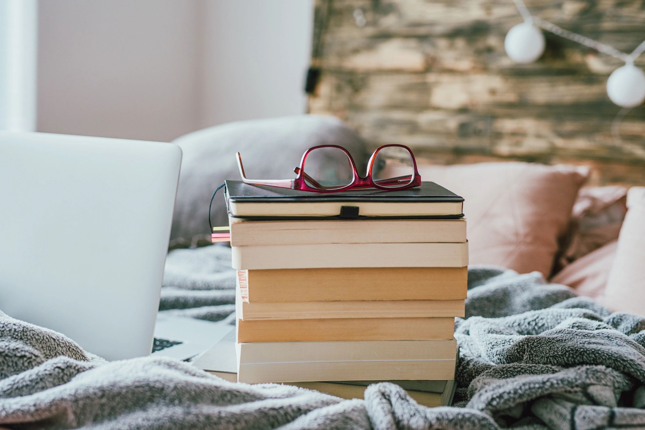 Pile of books with glasses and laptop